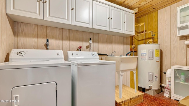washroom featuring washing machine and clothes dryer, wooden walls, cabinet space, wooden ceiling, and electric water heater