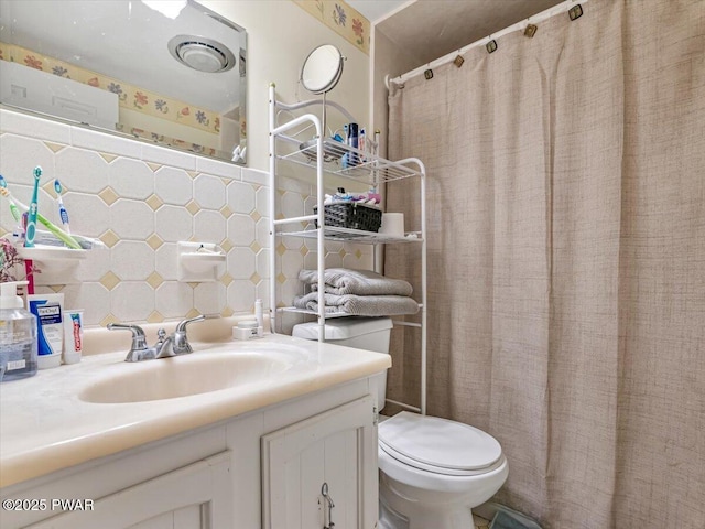 bathroom featuring toilet, vanity, and decorative backsplash