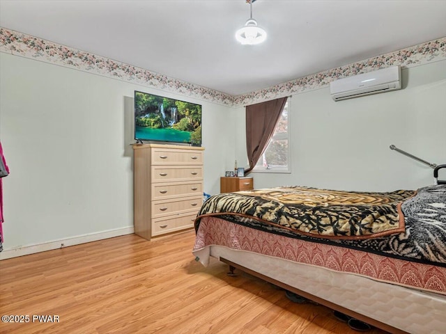 bedroom with light hardwood / wood-style flooring and an AC wall unit