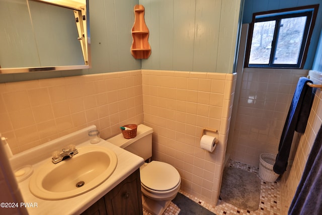 bathroom featuring vanity, toilet, and tile walls