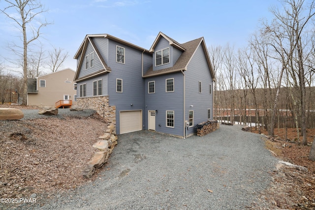 exterior space featuring driveway, an attached garage, and a shingled roof