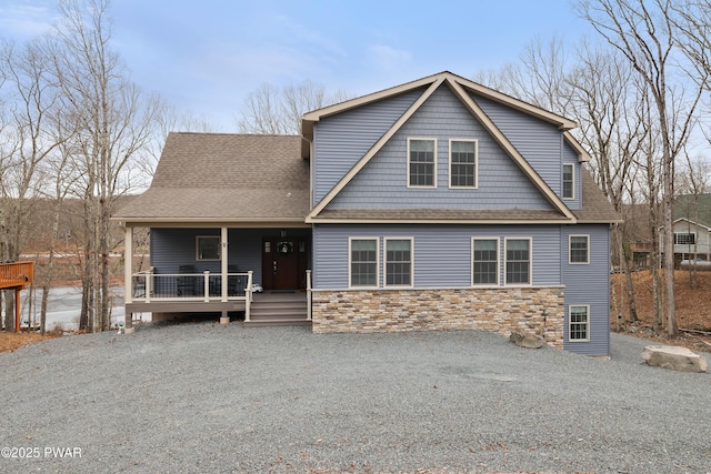 view of front of property with stone siding, covered porch, and roof with shingles