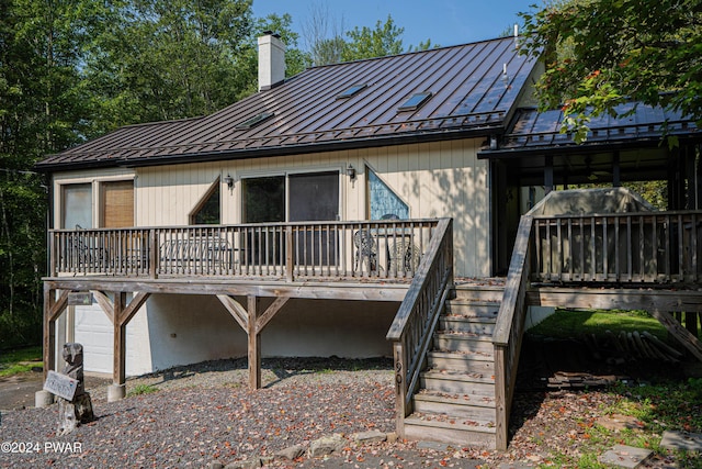 rear view of house featuring a garage and a wooden deck