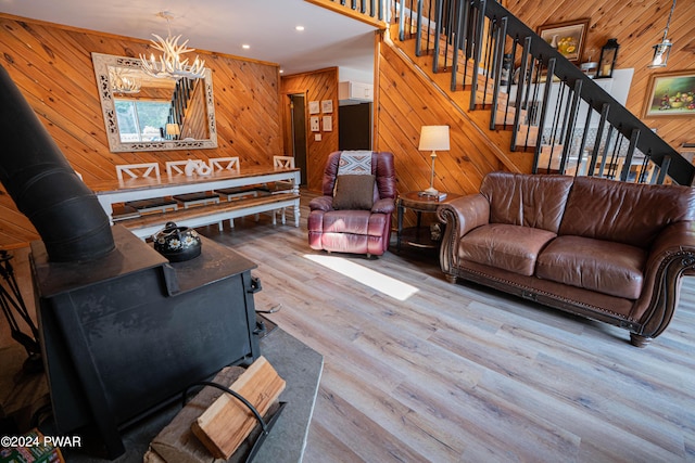 living room with a chandelier, wood walls, and light hardwood / wood-style flooring