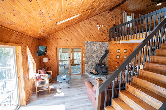 staircase with hardwood / wood-style flooring, vaulted ceiling with skylight, wooden ceiling, and a wood stove