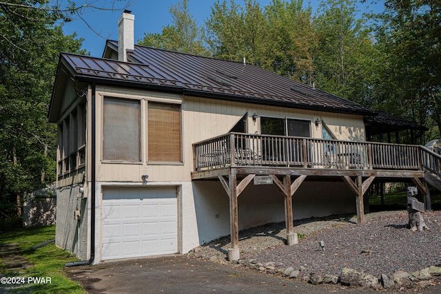 rear view of house featuring a garage and a wooden deck