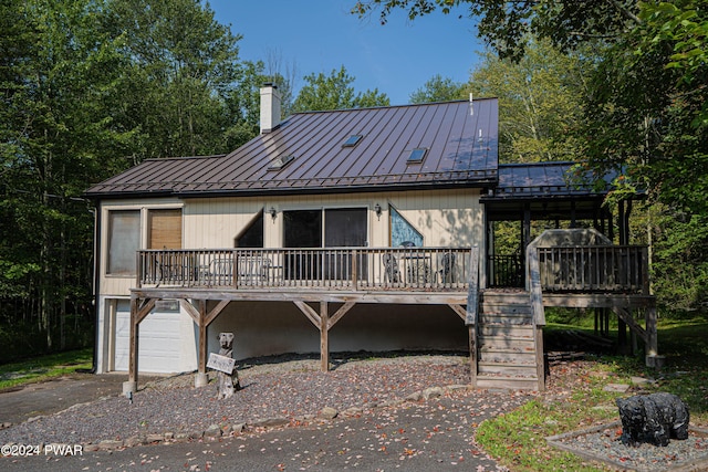 rear view of property with a garage and a wooden deck