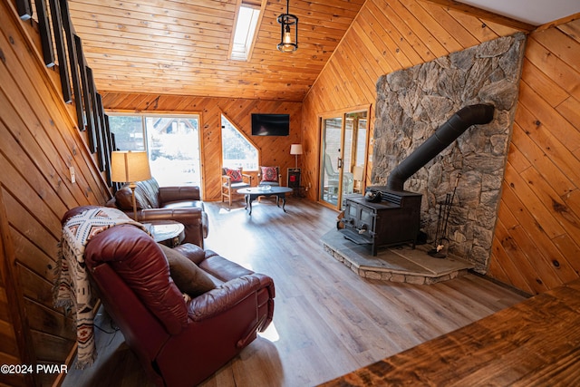 living room featuring a wood stove, wooden ceiling, high vaulted ceiling, wooden walls, and hardwood / wood-style flooring