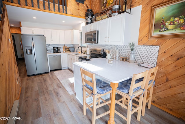 kitchen featuring decorative backsplash, appliances with stainless steel finishes, sink, white cabinets, and light hardwood / wood-style floors