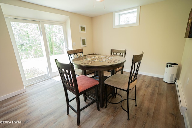 dining space featuring a wealth of natural light, wood-type flooring, and a baseboard heating unit