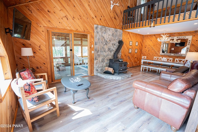 living room with high vaulted ceiling, hardwood / wood-style flooring, and a wood stove