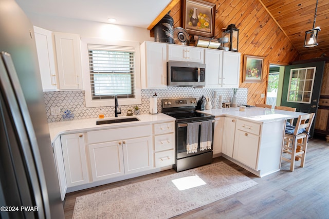 kitchen featuring sink, hanging light fixtures, stainless steel appliances, kitchen peninsula, and white cabinets