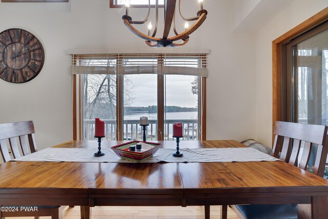 dining space with a water view, a healthy amount of sunlight, and a notable chandelier