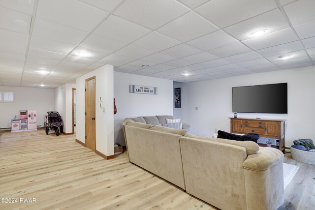 living room featuring light wood-type flooring and a drop ceiling