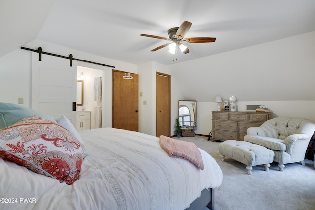 carpeted bedroom featuring ceiling fan, a barn door, vaulted ceiling, and ensuite bath