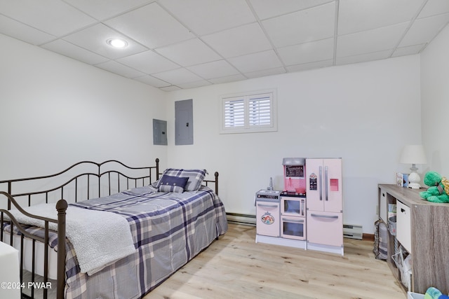 bedroom with electric panel, a drop ceiling, light hardwood / wood-style floors, and a baseboard heating unit