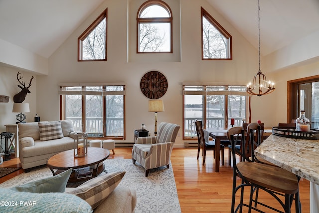 living room featuring an inviting chandelier, high vaulted ceiling, a baseboard radiator, and light wood-type flooring