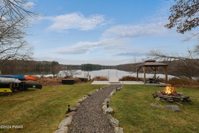 view of yard featuring a gazebo, a water view, a fire pit, and a dock