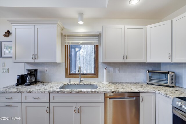 kitchen featuring stove, backsplash, white cabinets, sink, and dishwasher