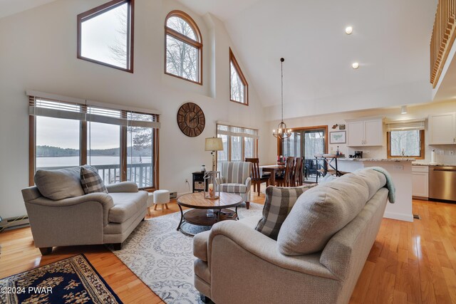 living room featuring high vaulted ceiling, a water view, a chandelier, and light wood-type flooring