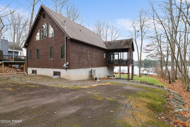 view of home's exterior with a wall unit AC and a water view