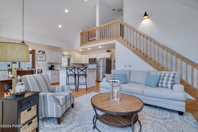 living room featuring light wood-type flooring and high vaulted ceiling