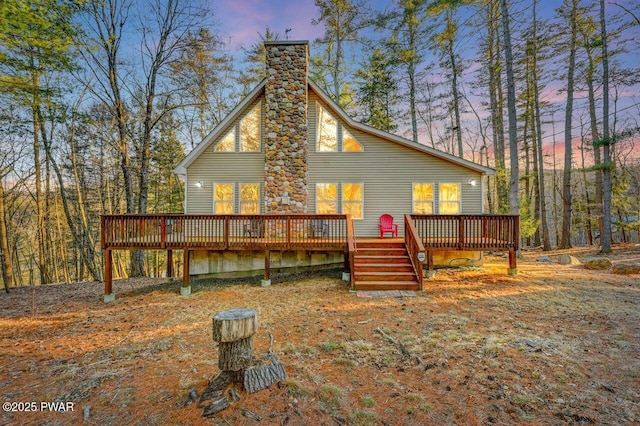 back of house at dusk with a chimney and a deck