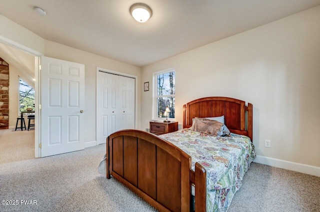 bedroom featuring light carpet, multiple windows, a closet, and baseboards