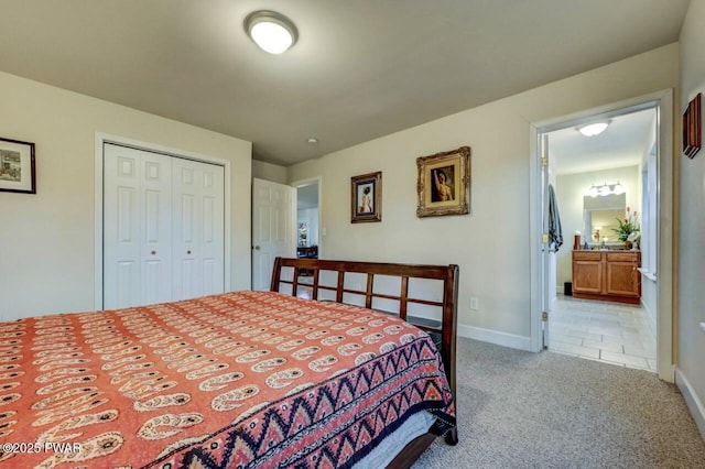 bedroom featuring ensuite bath, light colored carpet, a closet, and baseboards