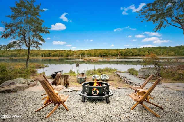 view of yard featuring a fire pit, a water view, and a view of trees