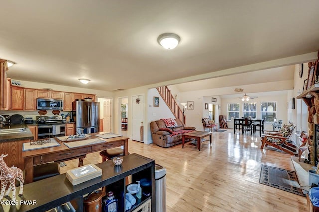 interior space with stairs, a fireplace, light wood-style floors, and a ceiling fan