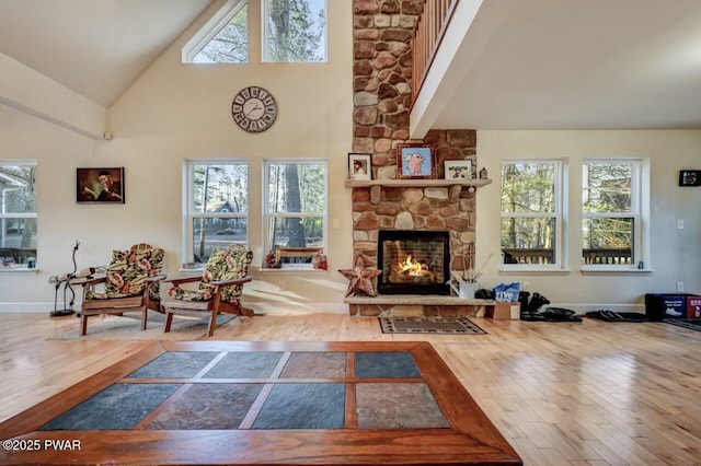 living area with wood finished floors, a fireplace, baseboards, and high vaulted ceiling