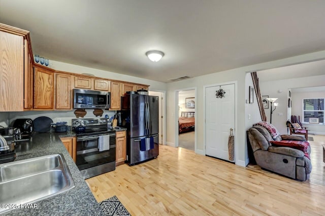 kitchen with stainless steel microwave, light wood-style flooring, freestanding refrigerator, electric stove, and a sink