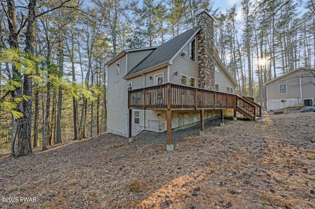 back of house with stairway, a chimney, a deck, and roof with shingles