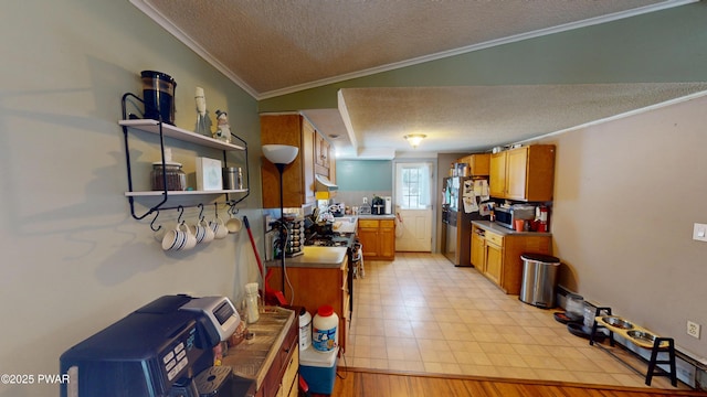 kitchen featuring a textured ceiling, under cabinet range hood, light countertops, appliances with stainless steel finishes, and crown molding