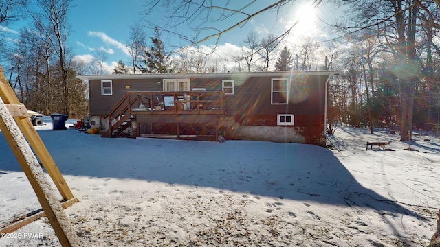 snow covered back of property featuring stairway and a deck