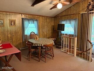 195 Conashaugh Trl, Milford, PA 18337 - dining area featuring vaulted ceiling, plenty of natural light, wood walls, ceiling fan, and light carpet