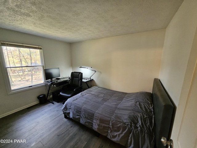 bedroom featuring dark hardwood / wood-style flooring and a textured ceiling