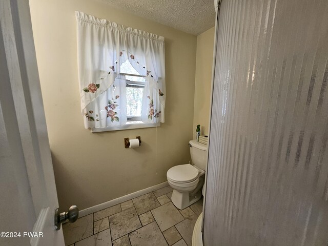 bathroom with a textured ceiling and toilet