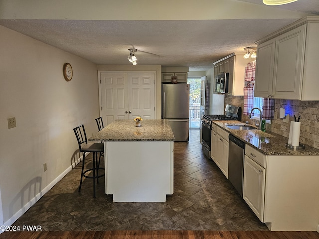 kitchen with sink, a center island, stainless steel appliances, decorative backsplash, and a breakfast bar