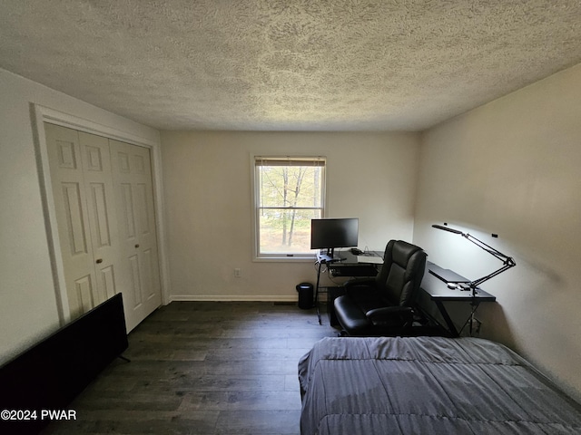 bedroom with dark hardwood / wood-style flooring, a textured ceiling, and a closet