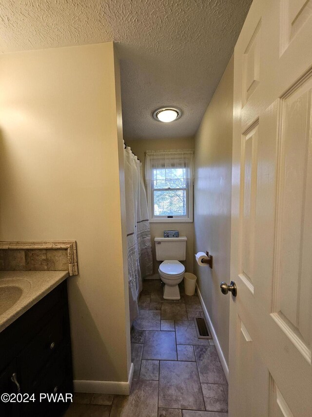 bathroom featuring a textured ceiling, vanity, and toilet