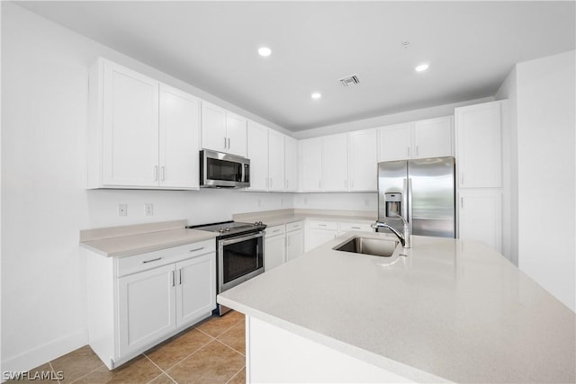 kitchen featuring light tile patterned flooring, a sink, stainless steel appliances, light countertops, and white cabinetry