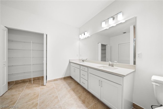 bathroom featuring double vanity, tile patterned floors, toilet, and a sink