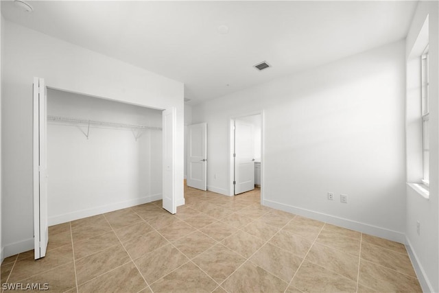 unfurnished bedroom with visible vents, baseboards, a closet, and light tile patterned flooring