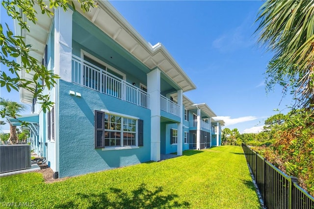 rear view of house featuring a yard, stucco siding, central AC, and fence