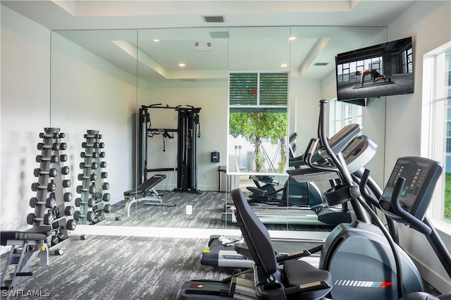 exercise room with a raised ceiling, recessed lighting, baseboards, and visible vents