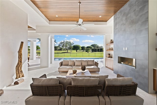 living area with a fireplace, tile walls, wood ceiling, a ceiling fan, and a raised ceiling