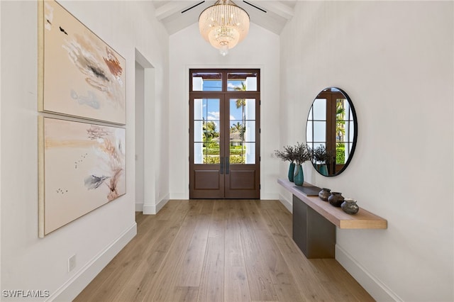 doorway with a notable chandelier, french doors, light wood-type flooring, and baseboards