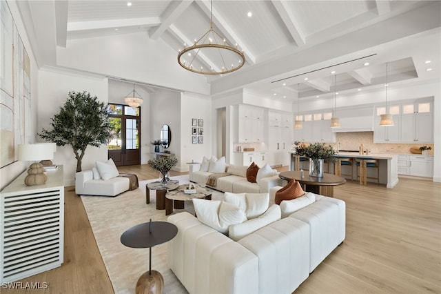 living room with light wood-type flooring, an inviting chandelier, high vaulted ceiling, and beam ceiling